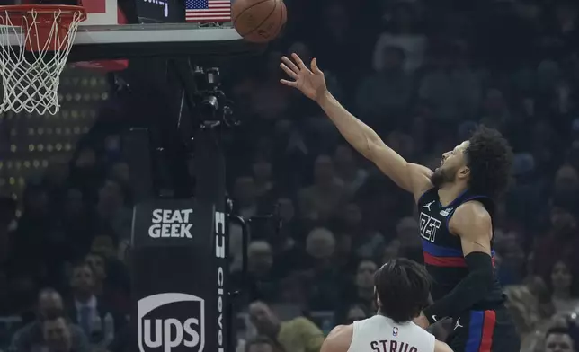 Detroit Pistons guard Cade Cunningham, right, shoots in front of Cleveland Cavaliers guard Max Strus, left, in the first half of an NBA basketball game, Monday, Jan. 27, 2025, in Cleveland. (AP Photo/Sue Ogrocki)