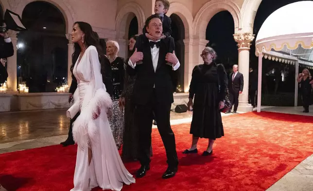 Elon Musk and his son, X AE A-Xii, arrive to a New Year's Eve party hosted by President-elect Donald Trump at Mar-a-Lago, Tuesday, Dec. 31, 2024, in Palm Beach, Fla. (AP Photo/Evan Vucci)