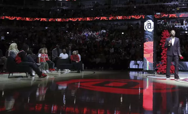 Former NBA player Derrick Rose, right, speaks as his family, left, watches during a half-time ceremony during an NBA basketball game between the New York Knicks and the Chicago Bulls, Saturday, Jan. 4, 2025, in Chicago. (AP Photo/Melissa Tamez)