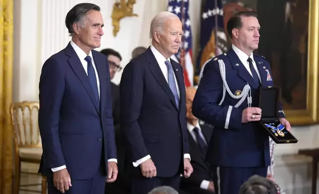 President Joe Biden, center, prepares to posthumously present the Presidential Medal of Freedom, the Nation's highest civilian honor, to former Sen. Mitt Romney, R-Utah, on behalf of his late father George Romney, in the East Room of the White House, Saturday, Jan. 4, 2025, in Washington. (AP Photo/Manuel Balce Ceneta)