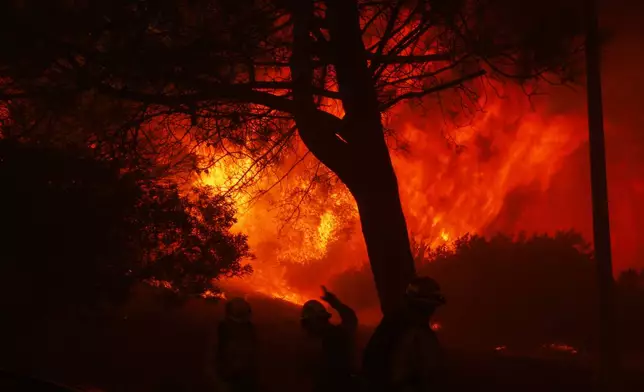 Firefighters stage in front of the advancing Palisades Fire in the Pacific Palisades neighborhood of Los Angeles, Tuesday, Jan. 7, 2025. (AP Photo/Etienne Laurent)