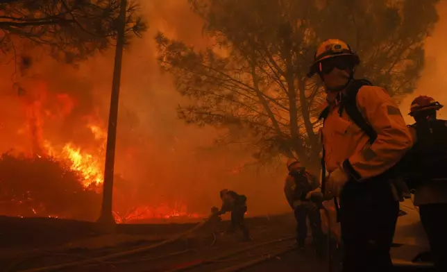 Firefighters battle the advancing Palisades Fire in the Pacific Palisades neighborhood of Los Angeles, Tuesday, Jan. 7, 2025. (AP Photo/Etienne Laurent)