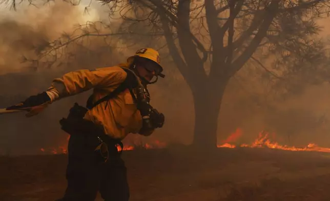 A firefighter battles the advancing Palisades Fire in the Pacific Palisades neighborhood of Los Angeles, Tuesday, Jan. 7, 2025. (AP Photo/Etienne Laurent)