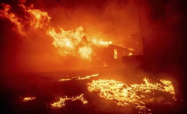 The Eaton Fire destroys a structure Tuesday, Jan. 7, 2025, in Altadena, Calif. (AP Photo/Ethan Swope)