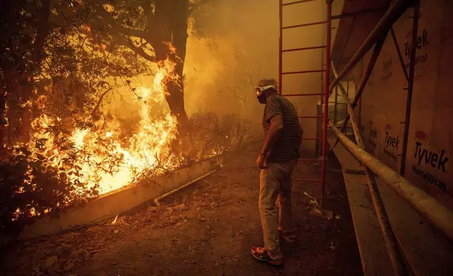 Will Adams watches as flames from the Palisades Fire close in on his property in the Pacific Palisades neighborhood of Los Angeles, Tuesday, Jan. 7, 2025. (AP Photo/Ethan Swope)