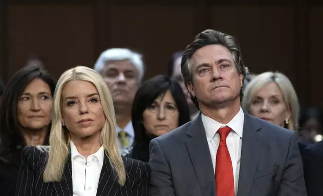 Pam Bondi, President-elect Donald Trump's choice to lead the Justice Department as attorney general, and her husband John Wakefield listen during the Senate Judiciary Committee for her confirmation hearing, at the Capitol in Washington, Wednesday, Jan. 15, 2025. (AP Photo/Ben Curtis)