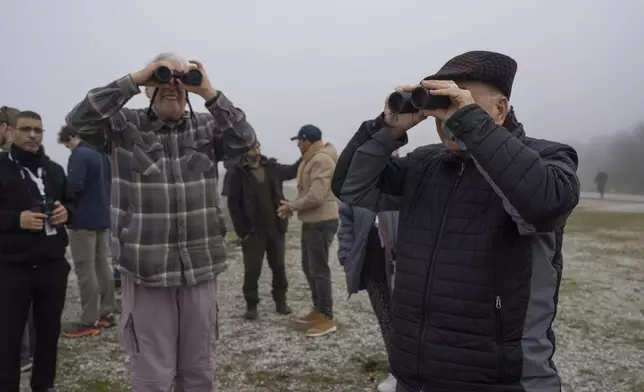 Yossi Leshem, professor emeritus at Tel Aviv University's School of Zoology, left, and retired Gen. Mansour Abu Rashid, former director of Jordanian military intelligence, watch through their binoculars for birds as fog covers the Karla lake, near the town of Stefanovikeio, Larissa, central Greece, Jan. 22, 2025. (AP Photo/Petros Giannakouris)