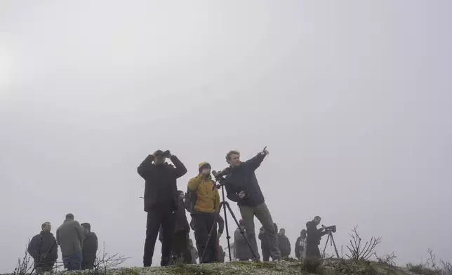 Birdwatchers look on through their binoculars as fog covers the Karla lake, near the town of Stefanovikeio, Larissa, central Greece, on Jan. 22, 2025. (AP Photo/Petros Giannakouris)