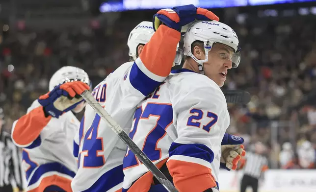 New York Islanders defenseman Scott Mayfield (24) celebrates with left wing Anders Lee (27) after Lee's goal during the first period of an NHL hockey game against the Vegas Golden Knights, Thursday, Jan. 9, 2025, in Las Vegas. (AP Photo/Ian Maule)