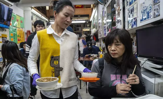 A waitress serves a customer at the family-run snake soup restaurant in Hong Kong, Monday, Jan. 6, 2025. (AP Photo/Chan Long Hei)