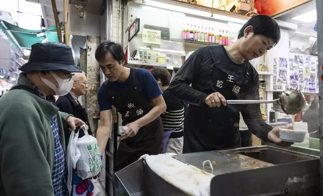 Waiters serve food to customers at the family-run snake soup restaurant in Hong Kong, Monday, Jan. 6, 2025. (AP Photo/Chan Long Hei)