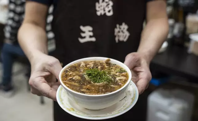 A waiter holds a bowl of snake soup at a restaurant in Hong Kong, Monday, Jan. 6, 2025. (AP Photo/Chan Long Hei)