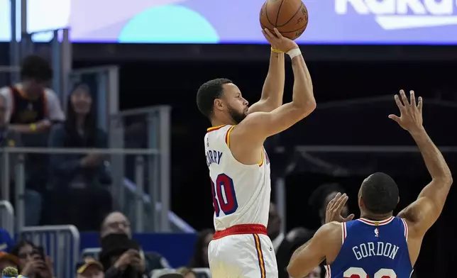 Golden State Warriors guard Stephen Curry, left, shoots a 3-point basket next to Philadelphia 76ers guard Eric Gordon during the first half of an NBA basketball game, Thursday, Jan. 2, 2025, in San Francisco. (AP Photo/Godofredo A. Vásquez)