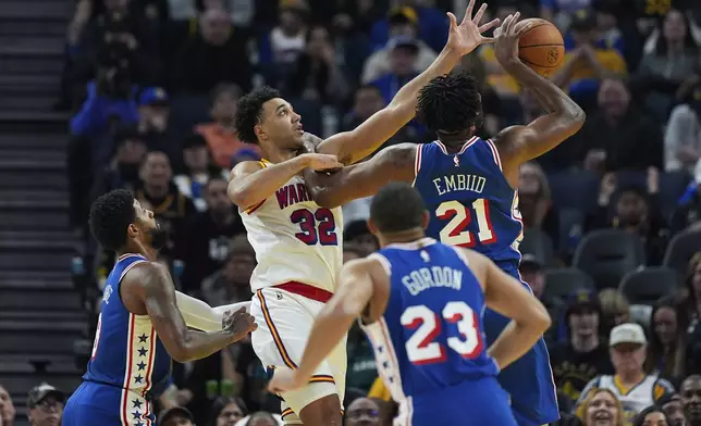 Golden State Warriors center Trayce Jackson-Davis (32) and Philadelphia 76ers center Joel Embiid (21) compete for a rebound during the first half of an NBA basketball game Thursday, Jan. 2, 2025, in San Francisco. (AP Photo/Godofredo A. Vásquez)