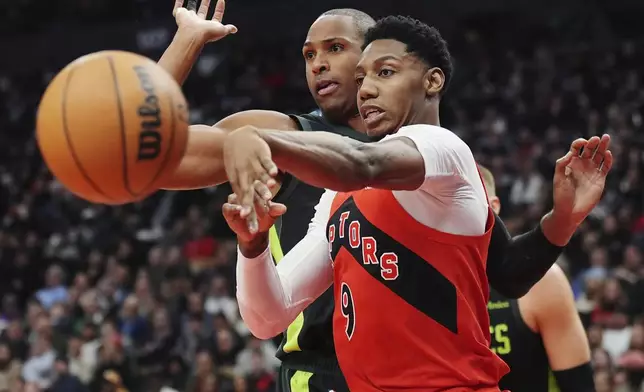 Toronto Raptors' RJ Barrett (9) makes a pass as Boston Celtics' Al Horford defends during the first half of an NBA basketball game in Toronto on Wednesday, Jan. 15, 2025. (Frank Gunn/The Canadian Press via AP)