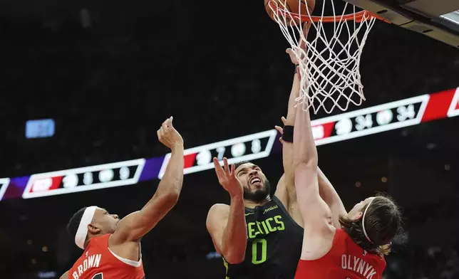 Boston Celtics' Jayson Tatum (0) shoots over Toronto Raptors' Kelly Olynyk as Bruce Brown looks on during the second half of an NBA basketball game in Toronto on Wednesday, Jan. 15, 2025. (Frank Gunn/The Canadian Press via AP)