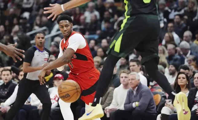 Toronto Raptors' RJ Barrett, left, makes a bounce pass past Boston Celtics' Derrick White, right, during the first half of an NBA basketball game in in Toronto on Wednesday, Jan. 15, 2025. (Frank Gunn/The Canadian Press via AP)