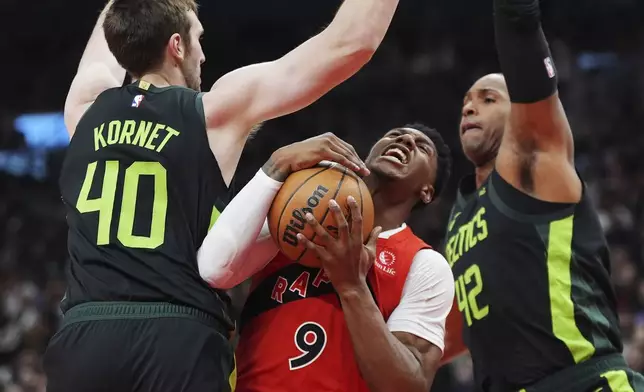 Toronto Raptors' RJ Barrett, left, makes a bounce pass past Boston Celtics' Derrick White, right, during the first half of an NBA basketball game in Toronto on Wednesday, Jan. 15, 2025. (Frank Gunn/The Canadian Press via AP)