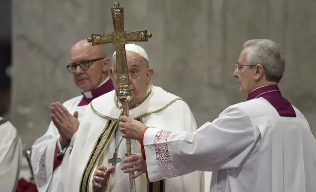 Pope Francis, center, holds the cross as he presides over an Epiphany mass in St.Peter's Basilica, at the Vatican, Monday, Jan. 6, 2025. (AP Photo/Alessandra Tarantino)