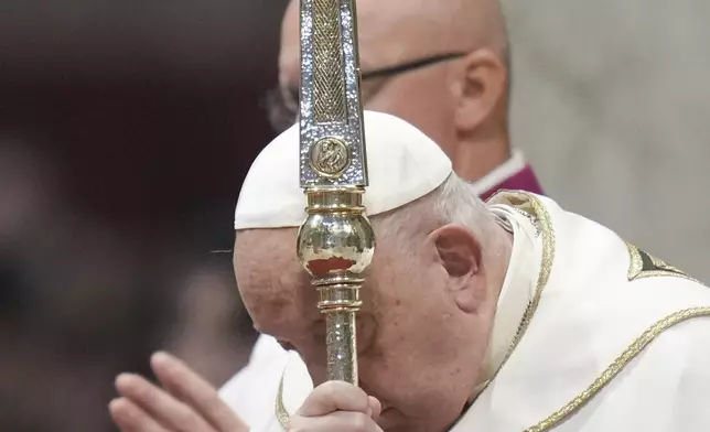 Pope Francis holds the cross as he presides over an Epiphany mass in St.Peter's Basilica, at the Vatican, Monday, Jan. 6, 2025. (AP Photo/Alessandra Tarantino)