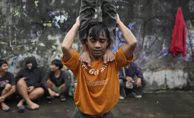 Members of dragon dance club Naga Merah Putih (Red White Dragon) which is named after Indonesian national colors, Mumammad Fadil, top, and Muhammad Ilman, bottom, train ahead of a performance, in Bogor, West Java, Indonesia, Friday, Jan. 24, 2025. (AP Photo/Dita Alangkara)