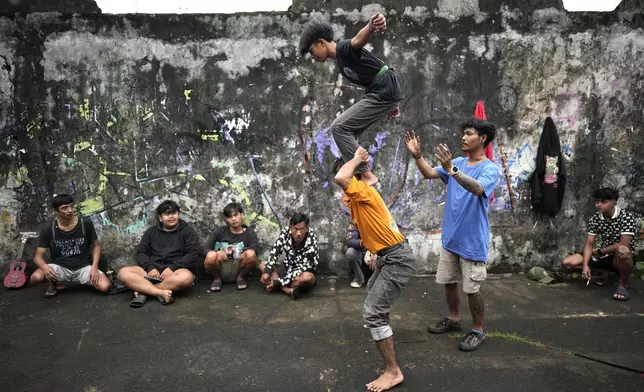 Members of dragon dance club Naga Merah Putih (Red White Dragon), named after Indonesian national colors, Mumammad Fadil, top, and Muhammad Ilman, bottom, practice their dance movements as Aji Permana, right assists, in Bogor, West Java, Indonesia, Friday, Jan. 24, 2025. (AP Photo/Dita Alangkara)
