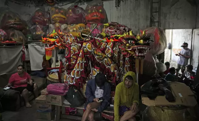 Members of dragon dance club Naga Merah Putih (Red White Dragon) which is named after Indonesian national colors, sit near dragon and lion puppets at the in Bogor, West Java, Indonesia, Thursday, Jan. 23, 2025. (AP Photo/Dita Alangkara)