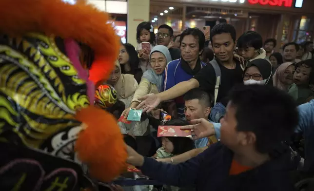 People give "angpau," an envelope containing money traditionally given during Chinese holidays or for special occasions, to members of dragon dance club Naga Merah Putih (Red White Dragon) after a performance at a shopping mall in Bogor, West Java, Indonesia, Sunday, Jan. 26, 2025. (AP Photo/Dita Alangkara)