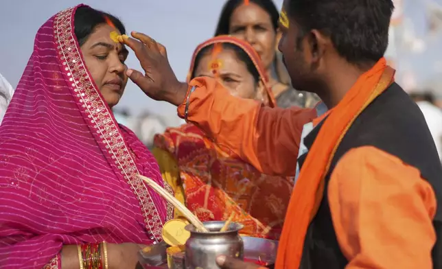 A Hindu priest puts a sacred mark on the forehead of a devotee at the confluence of the Ganges, the Yamuna, and the Saraswati rivers during the 45-day-long Maha Kumbh festival in Prayagraj, India, Tuesday, Jan. 28, 2025. (AP Photo/Deepak Sharma)