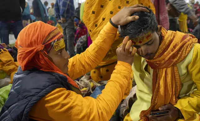 A Hindu devotee gets sacred marks painted on his forehead by a priest at the confluence of the Ganges, the Yamuna, and the Saraswati rivers on the first day of the 45-day-long Maha Kumbh festival in Prayagraj, India, Monday, Jan. 13, 2025. (AP Photo/Ashwini Bhatia)