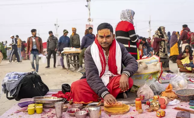 A Hindu priest, who puts sacred marks on devotees' foreheads, sits at his stall at the confluence of the Ganges, the Yamuna, and the Saraswati rivers during the 45-day-long Maha Kumbh festival in Prayagraj, India, Tuesday, Jan. 14, 2025. (AP Photo/Ashwini Bhatia)