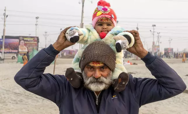 Bhagwat Prasad Tiwari and his granddaughter wear sacred marks reading 'Shree Ram' stamped in vermillion on their foreheads as they leave after bathing at the confluence of the Ganges, the Yamuna, and the Saraswati rivers the day before the 45-day-long Maha Kumbh festival in Prayagraj, India, Sunday, Jan. 12, 2025. (AP Photo/Ashwini Bhatia)