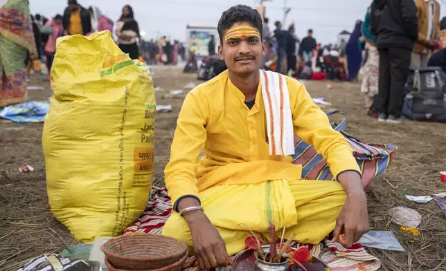 Hindu priest Anuj Kumar Tiwari, who puts sacred marks on devotees' foreheads, sits at his stall at the confluence of the Ganges, the Yamuna, and the Saraswati rivers during the 45-day-long Maha Kumbh festival in Prayagraj, India, Tuesday, Jan. 14, 2025. (AP Photo/Ashwini Bhatia)