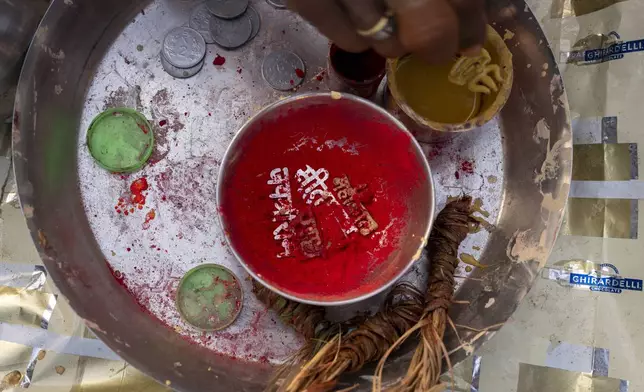 Tools for sacred marks, sandalwood paste, vermillion powder and metal stamps of Hindu gods' names are placed in a tray by a Hindu priest at the confluence of the Ganges, the Yamuna, and the Saraswati rivers during the 45-day-long Maha Kumbh festival in Prayagraj, India, Tuesday, Jan. 14, 2025. (AP Photo/Ashwini Bhatia)