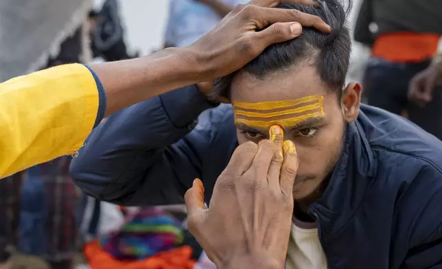A Hindu devotee gets a sacred mark on his forehead after bathing at the confluence of the Ganges, the Yamuna, and the Saraswati rivers during the 45-day-long Maha Kumbh festival in Prayagraj, India, Tuesday, Jan. 14, 2025. (AP Photo/Ashwini Bhatia)