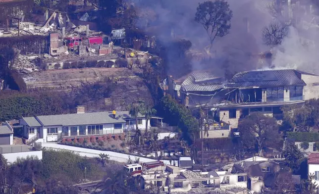 Firefighters protect what is left of homes from the Palisades Fire, Thursday, Jan. 9, 2025, in Malibu, Calif. (AP Photo/Mark J. Terrill)