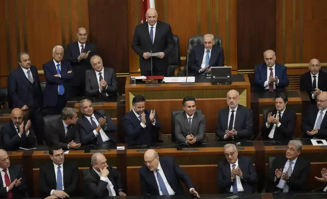 Lebanese cabinet ministers applaud the newly-elected Lebanese President Joseph Aoun, standing at the top, as gives his first speech at Parliament after being sworn in as president in Beirut, Lebanon, Thursday, Jan. 9, 2025.(AP Photo/Hussein Malla)