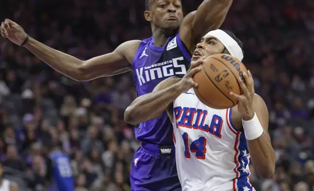 Philadelphia 76ers guard Ricky Council IV (14) drives to the basket past Sacramento Kings guard De'Aaron Fox during the first half of an NBA basketball game in Sacramento, Calif., Wednesday, Jan. 1, 2025. (AP Photo/Randall Benton)