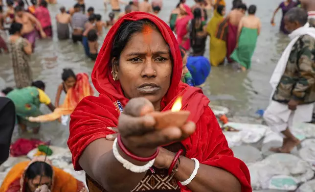 A Hindu pilgrim offers prayer with an oil lamp after taking a holy dip at Hooghly River on the auspicious occasion of Makar Sankranti, in Kolkata, India, Tuesday, Jan. 14, 2025. (AP Photo/Bikas Das)