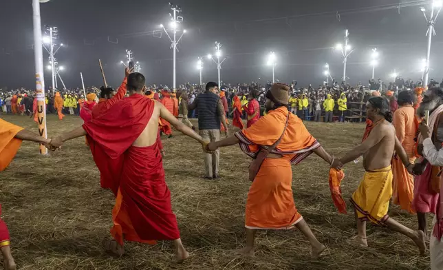 Followers make a barrier to the path on which senior Hindu ascetics and holy men walk in a procession to bathe at the confluence of the Ganges, the Yamuna and the mythical Saraswati rivers on the second day of the 45-day-long Maha Kumbh festival in Prayagraj, India, Tuesday, Jan. 14, 2025. (AP Photo/Ashwini Bhatia)