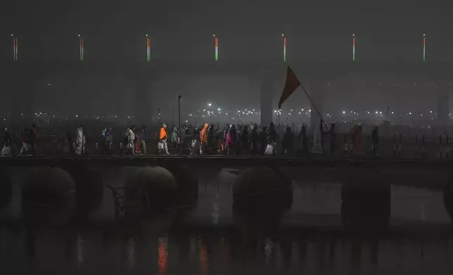 Hindu devotees cross a pontoon bridge after taking a dip at Sangam, the confluence of the Rivers Ganges, Yamuna and mythical Saraswati on one of the most auspicious day Makar Sankranti, for the Mahakumbh festival, which is one of the world's largest religious gatherings, celebrated every 12 years in Prayagraj, in the northern Indian state of Uttar Pradesh, India, Tuesday, Jan. 14, 2025. (AP Photo/Rajesh Kumar Singh)