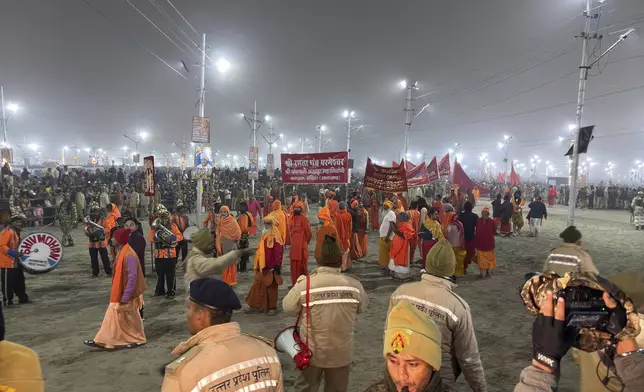 Hindus wait for a holy procession at the confluence of the Ganges, the Yamuna and the mythical Saraswati rivers on Makar Sankranti, an auspicious bathing day of the 45-day-long Maha Kumbh festival in Prayagraj, India, Tuesday, Jan. 14, 2025. (AP Photo/Ashwini Bhatia)