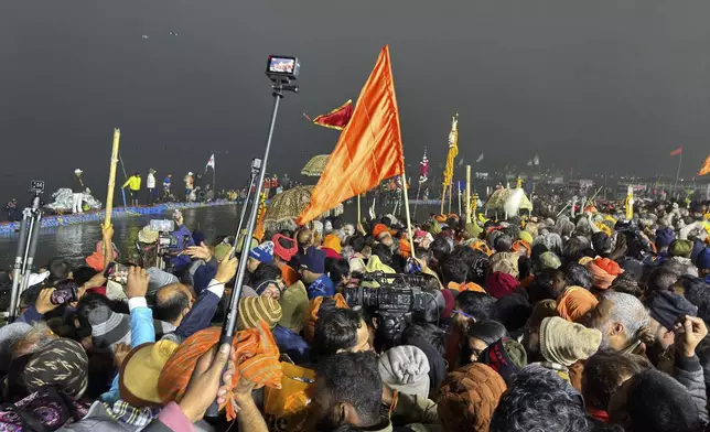Devotees throng the banks where ascetics are bathing at the confluence of the Ganges, the Yamuna and the mythical Saraswati rivers on Makar Sankranti, an auspicious bathing day of the 45-day-long Maha Kumbh festival in Prayagraj, India, Tuesday, Jan. 14, 2025. (AP Photo/Ashwini Bhatia)