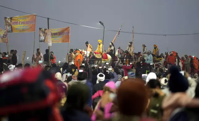 Naga Sadhus of Niranjani Akhara arrive for ritualistic dip at Sangam, the confluence of the Rivers Ganges, Yamuna and mythical Saraswati on one of the most auspicious day Makar Sankranti, for the Maha Kumbh festival in Prayagraj, India, Tuesday, Jan. 14, 2025. (AP Photo/Rajesh Kumar Singh)