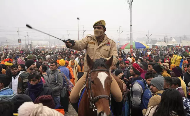 A policeman controls the crowd at Sangam, the confluence of the Rivers Ganges, Yamuna and mythical Saraswati on one of the most auspicious day Makar Sankranti, for the Maha Kumbh festival in Prayagraj, India, Tuesday, Jan. 14, 2025. (AP Photo/Rajesh Kumar Singh)