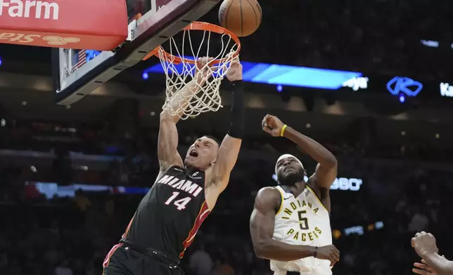 Miami Heat guard Tyler Herro (14) attempts a basket as Indiana Pacers forward Jarace Walker (5) defends during the first half of an NBA basketball game Thursday, Jan. 2, 2025, in Miami. (AP Photo/Lynne Sladky)