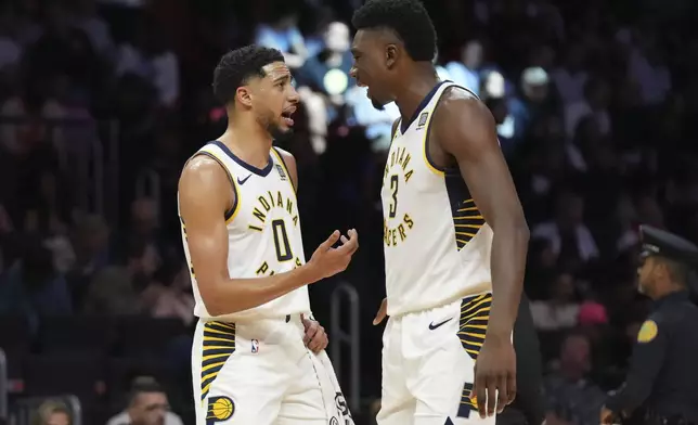 Indiana Pacers guard Tyrese Haliburton (0) talk with center Thomas Bryant (3) during the first half of an NBA basketball game against the Miami Heat Thursday, Jan. 2, 2025, in Miami. (AP Photo/Lynne Sladky)