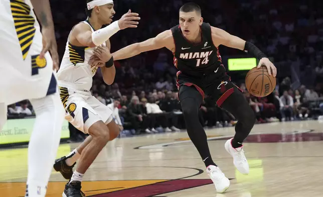 Miami Heat guard Tyler Herro (14) drives to the basket as Indiana Pacers guard Andrew Nembhard, left, defends during the first half of an NBA basketball game Thursday, Jan. 2, 2025, in Miami. (AP Photo/Lynne Sladky)