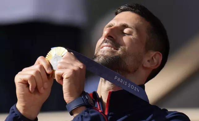 FILE - Serbia's Novak Djokovic watches his gold medal after defeating Spain's Carlos Alcaraz in the men's singles tennis final at the Roland Garros stadium during the 2024 Summer Olympics, Sunday, Aug. 4, 2024, in Paris, France. (AP Photo/Manu Fernandez, File)