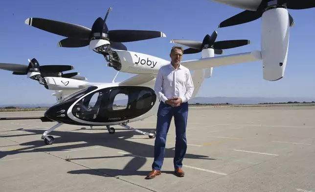 JoeBen Bevirt, CEO of Joby Aviation, stands next to an "electric vertical take-off and landing" aircraft, also known as an eVTOL, in Marina, Calif. on Monday, Oct. 7, 2024. (AP Photo/Terry Chea)